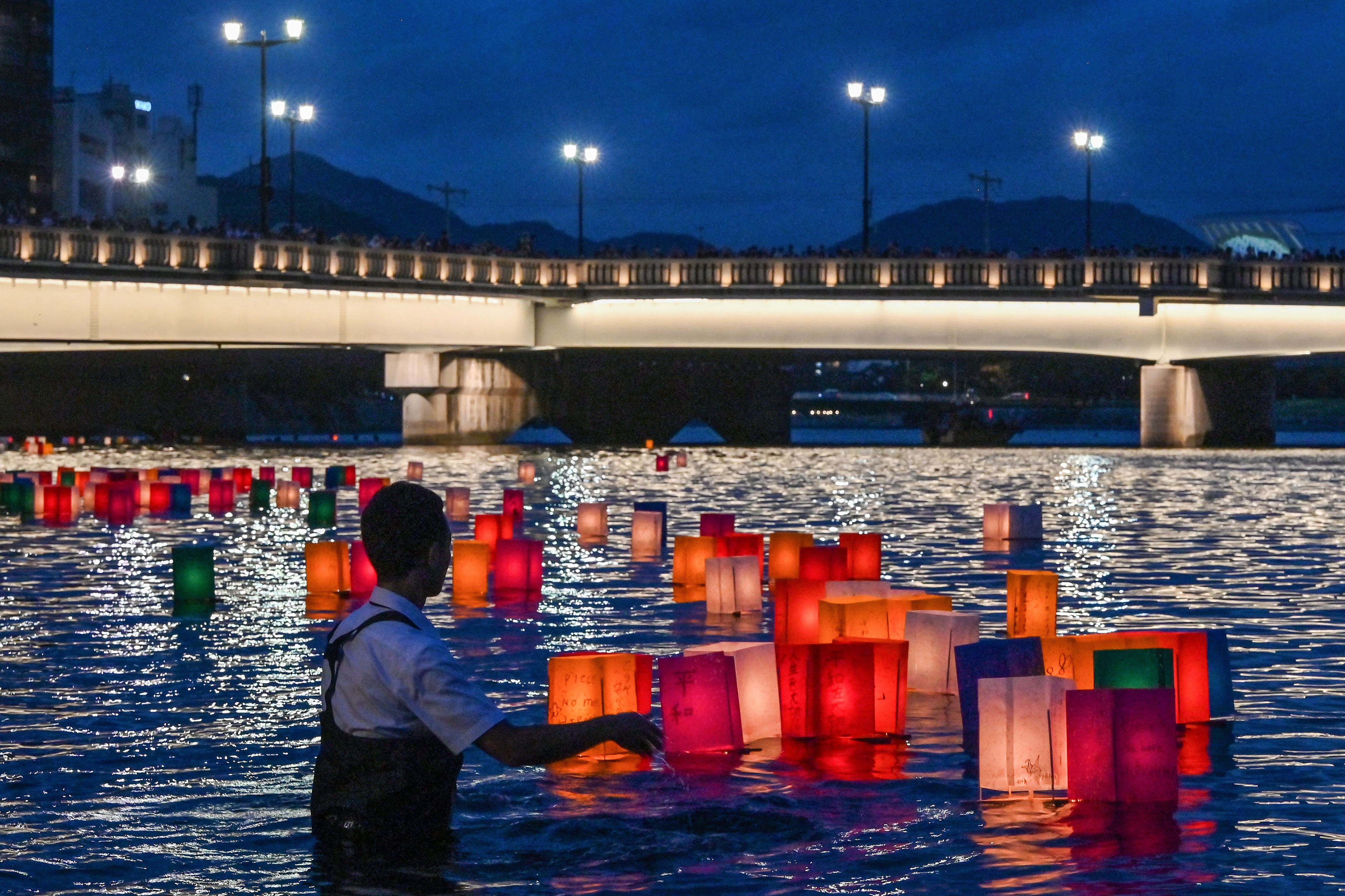 Un voluntario empuja linternas de papel hacia el río Motoyasu después de que los visitantes las soltaran para conmemorar el 80.º aniversario del primer ataque con bomba atómica del mundo, en la ciudad de Hiroshima el 6 de agosto de 2025. (Foto de Richard A. Brooks / AFP)