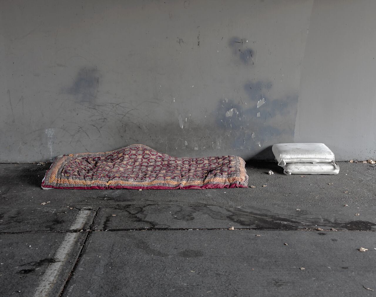 homeless person's bed and pillows under bridge