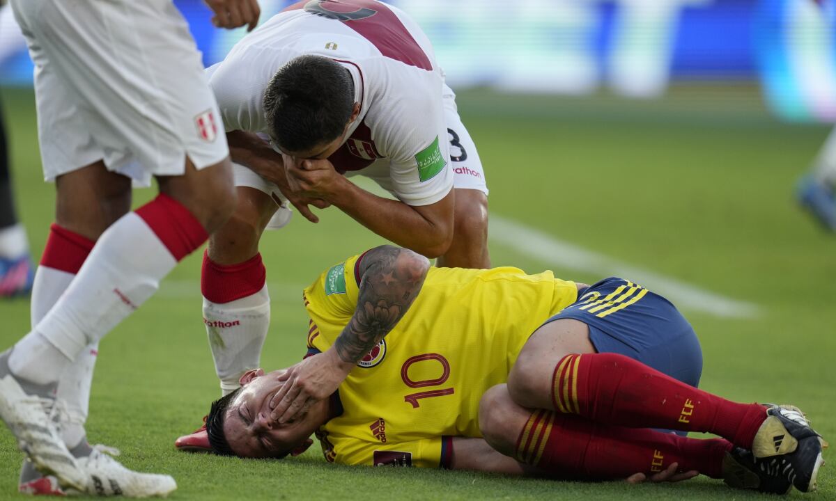 Peru's Aldo Corzo taunts Colombia's James Rodriguez after falling on the pitch during a qualifying soccer match for the FIFA World Cup Qatar 2022 at the Roberto Melendez stadium in Barranquilla, Colombia, Friday, Jan. 28, 2022. (AP/Fernando Vergara)