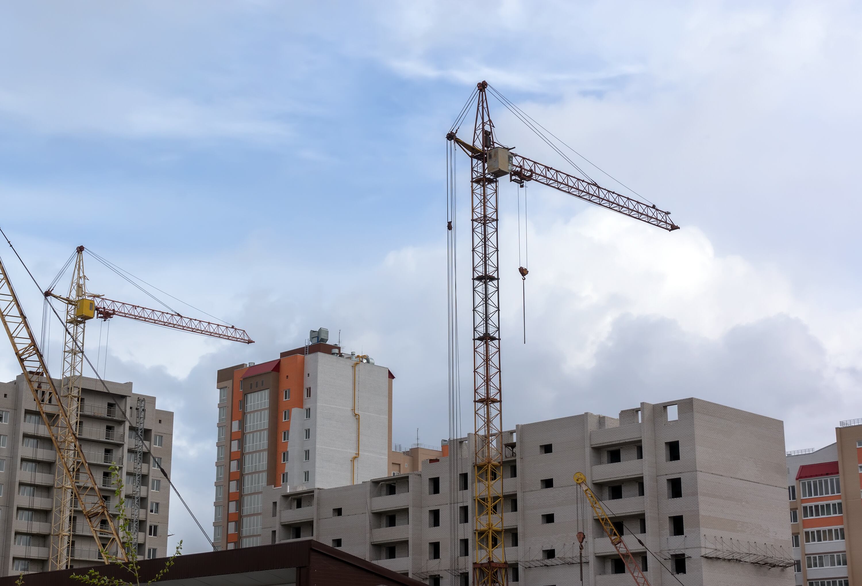 dos grúa torre alta y edificio en construcción contra el cielo oscuro.