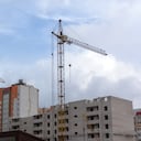 dos grúa torre alta y edificio en construcción contra el cielo oscuro.
