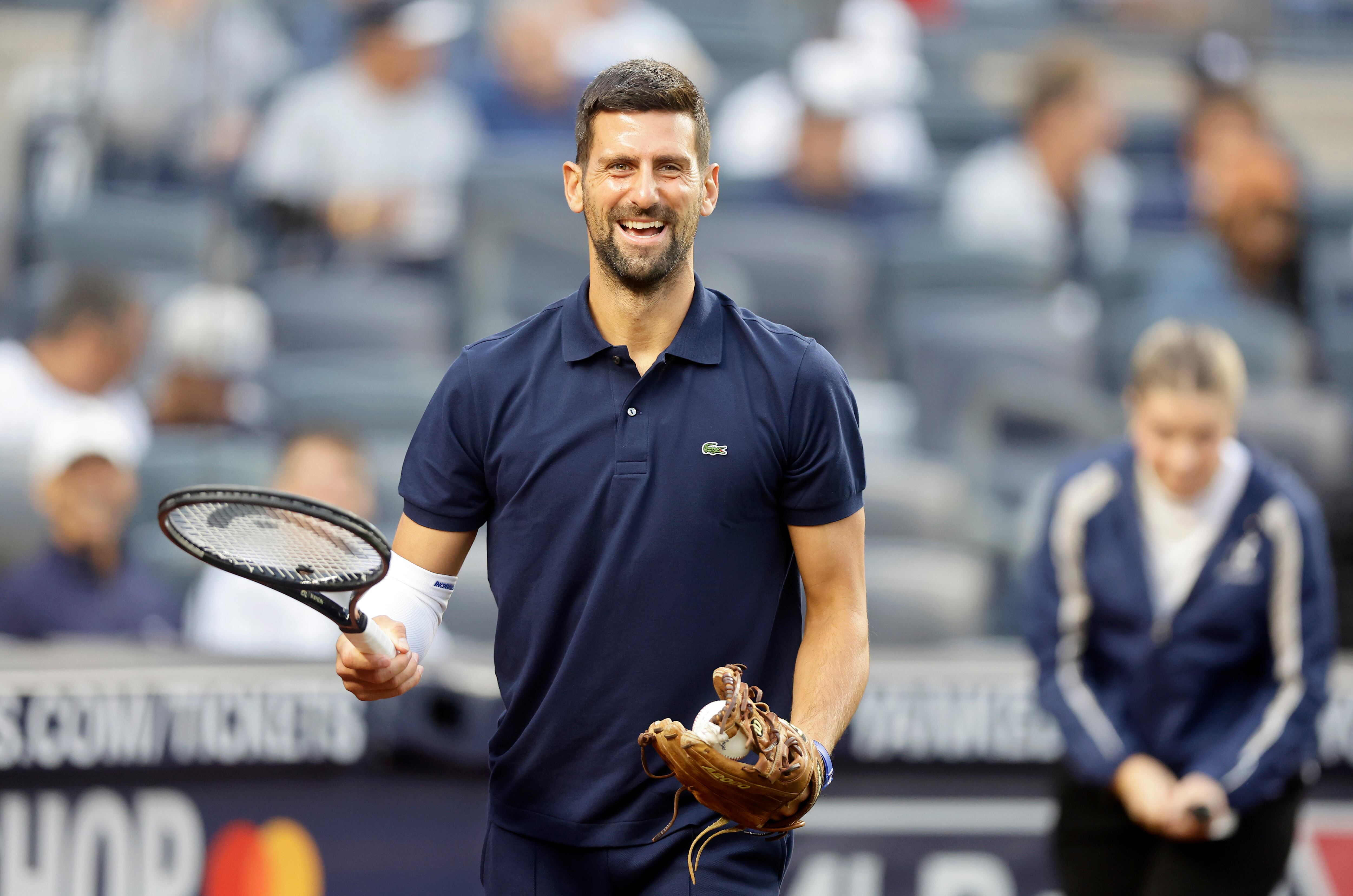 NEW YORK, NEW YORK - AUGUST 21: Tennis player Novak Djokovic has a laugh carrying his tennis racquet before throwing the ceremonial first pitch prior to a game between the New York Yankees and Boston Red Sox at Yankee Stadium on August 21, 2025 in New York City. (Photo by Jim McIsaac/Getty Images)