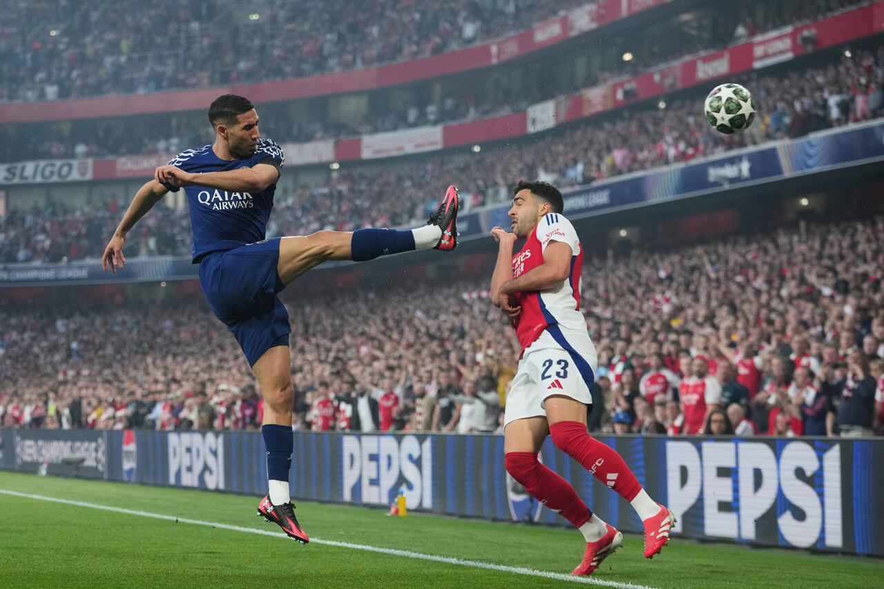 PSG's Achraf Hakimi fights for the ball with Arsenal's Mikel Merino, right, during the Champions League semifinal first leg soccer match between Arsenal and Paris Saint-Germain at Arsenal Stadium in London, England, Tuesday, April 29, 2025. (AP Photo/Kin Cheung)