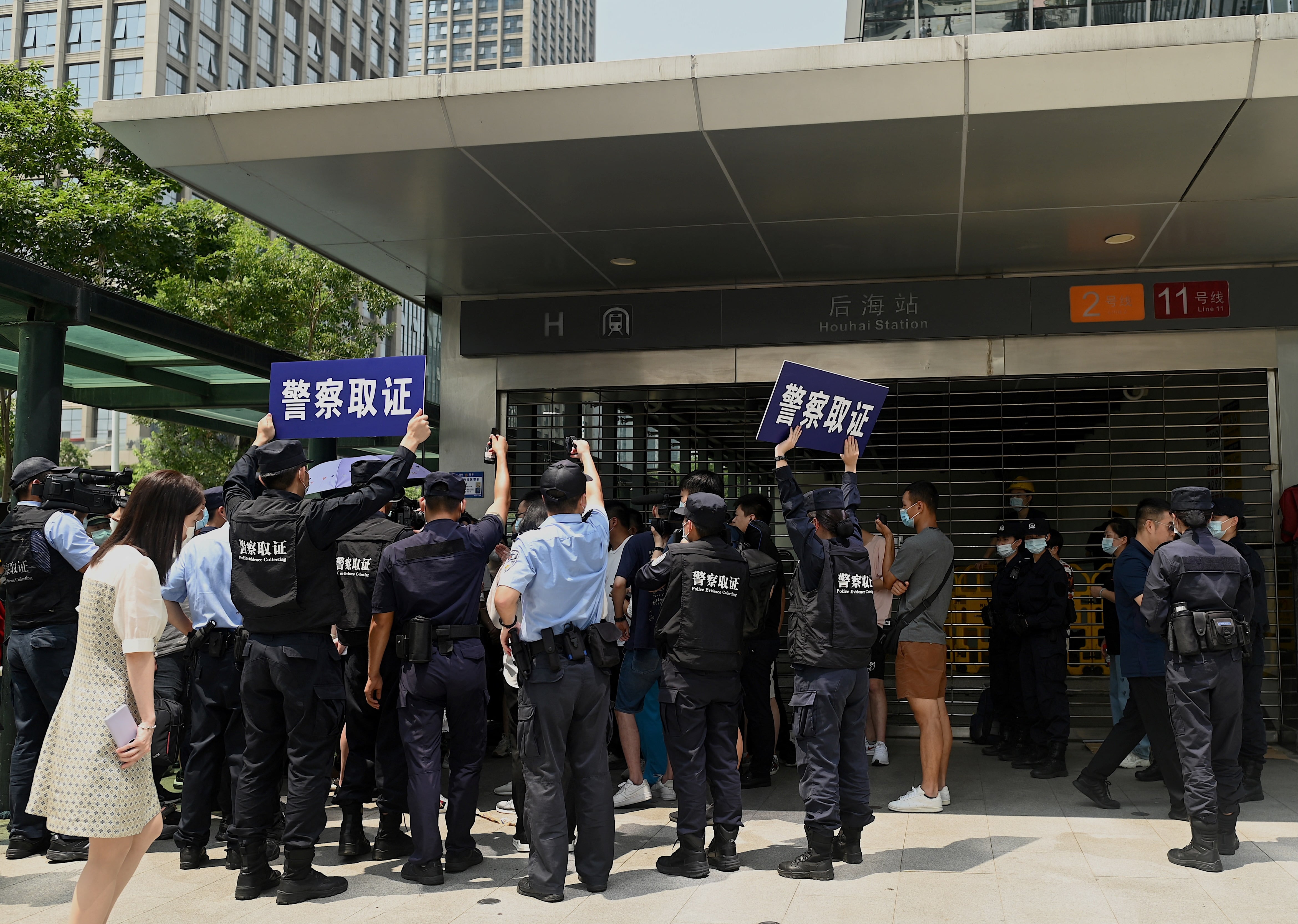 TOPSHOT - Police officers look at people gathering at the Evergrande headquarters in Shenzhen, southeastern China on September 16, 2021, as the Chinese property giant said it is facing "unprecedented difficulties" but denied rumours that it is about to go under. (Photo by Noel Celis / AFP)