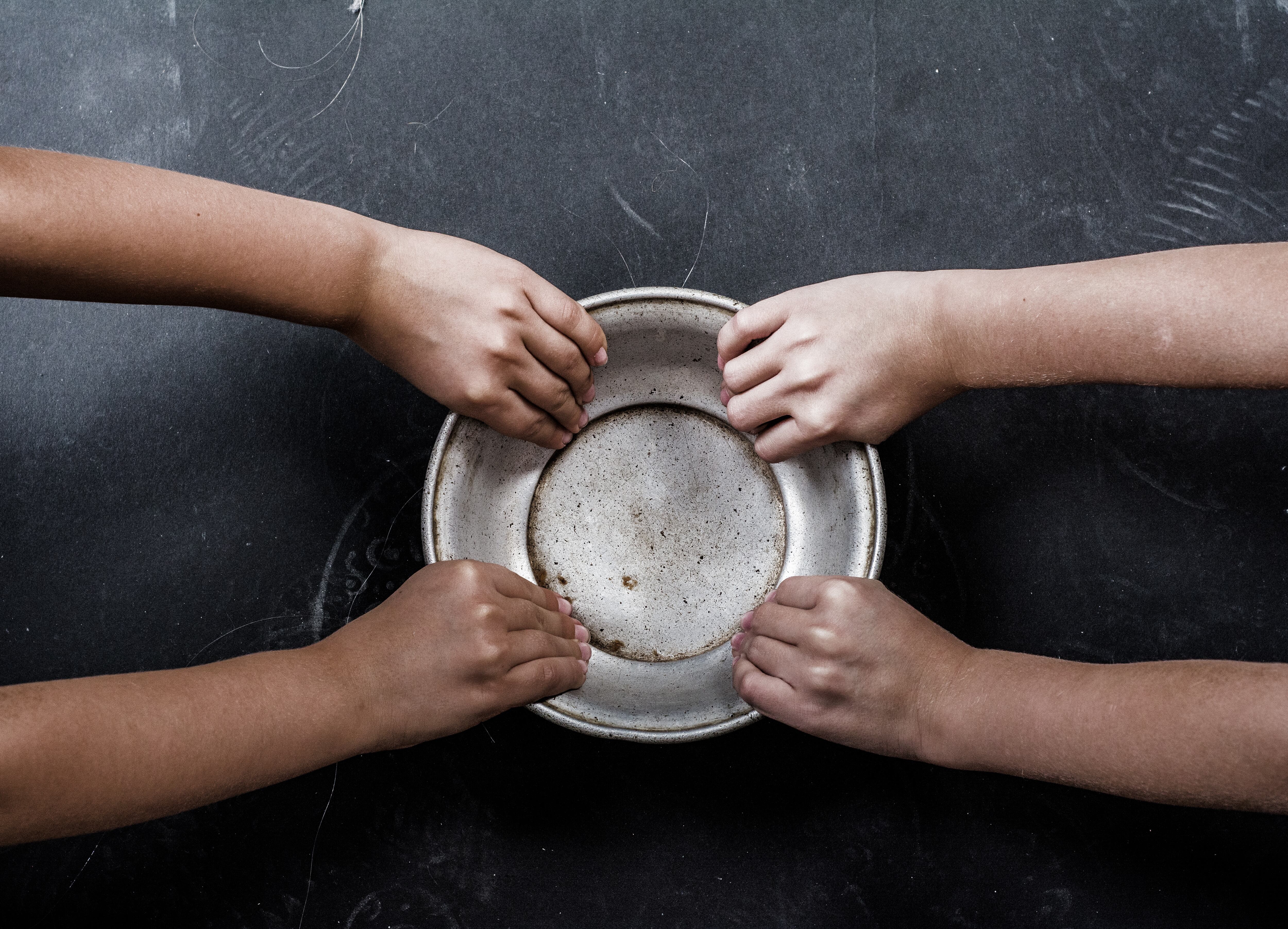 Dos pares de manos de niños sostienen una placa de metal.