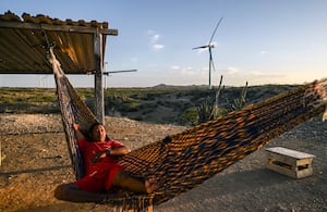 Un hombre descansa en una hamaca frente a un parque eólico en La Guajira, una imagen que refleja el encuentro entre el territorio, las comunidades y los nuevos proyectos de energías renovables en Colombia.