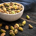 Top view of a bowl filled with organic pistachios shot on rustic wood table.