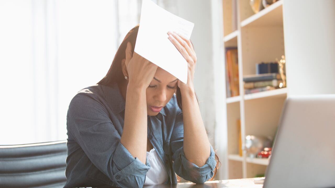 Anxious mixed race woman paying bills on laptop