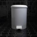 A closed garbage bin on a black-tiled bathroom floor.