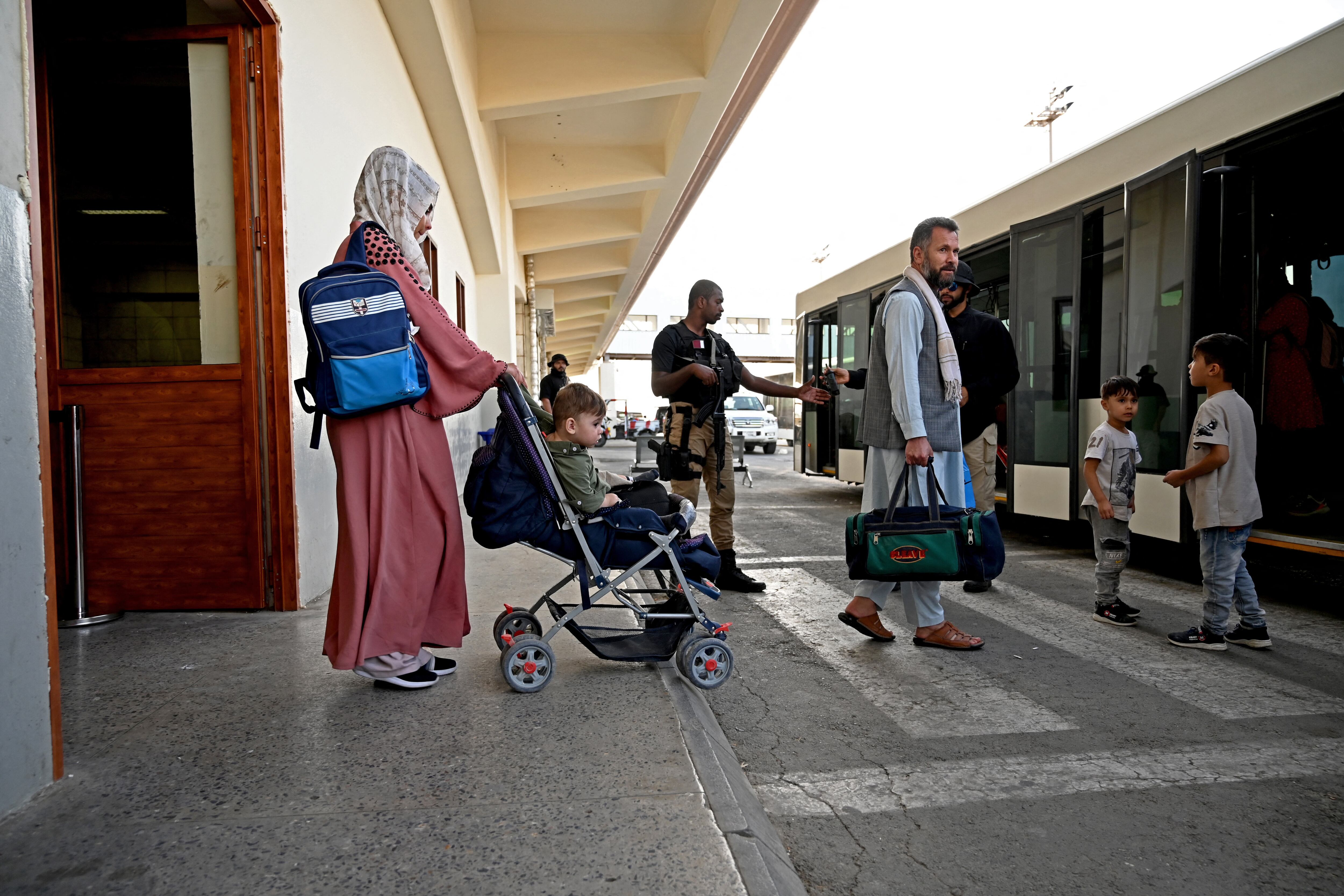n personal de seguridad de Qatar (C) hace guardia cuando los pasajeros ingresan en un autobús de enlace antes de abordar un avión de Qatar Airways en el aeropuerto de Kabul el 9 de septiembre de 2021. - Unos 200 pasajeros, incluidos ciudadanos estadounidenses, salieron del aeropuerto de Kabul el 9 de septiembre de 2021. , en el primer vuelo que transportaba a extranjeros fuera de la capital afgana desde que terminó una evacuación liderada por Estados Unidos el 30 de agosto (Foto de WAKIL KOHSAR / AFP).