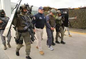 En esta foto publicada por la Oficina de Prensa de la Presidencia de Colombia aparece la escolta policial de Dairo Antonio Úsuga, centro, también conocido como "Otoniel", líder del violento cartel Clan del Golfo antes de su extradición a EEUU en un aeropuerto militar en Bogotá, Colombia, el miércoles 4 de mayo de 2022. (Oficina de Prensa de la Presidencia de Colombia via AP)