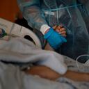 Chaplain Kristin Michealsen holds the hand of a deceased COVID-19 patient while talking on the phone with the patient's family member at Providence Holy Cross Medical Center in the Mission Hills section of Los Angeles on Saturday, Jan. 9, 2021. "I have never seen this much of death and suffering," said Michealsen, who has been a chaplain for 13 years. "I often tell families that I'm holding their loved one's hand when they can't and that I am with them when they are dying when they can't be." (AP Photo/Jae C. Hong)