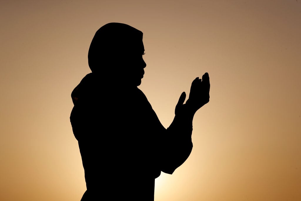 Silueta de mujer musulmana en abaya rezando con las manos en el aire al atardecer. Concepto de oración religiosa. Emiratos Árabes Unidos. (Foto de: Philippe Lissac/Godong/Universal Images Group vía Getty Images)