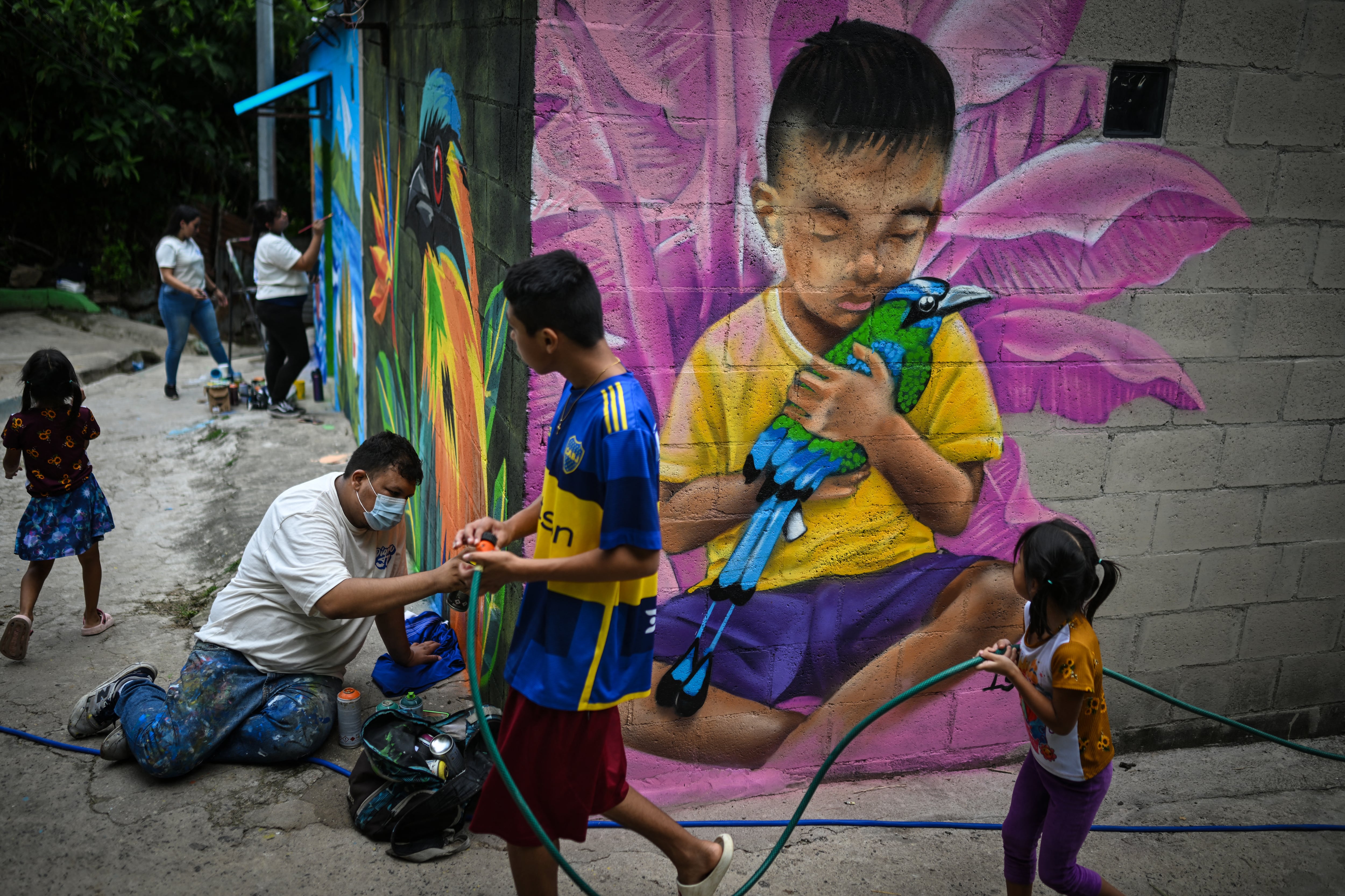 Carlos Clímaco (izq.) pinta un mural junto a varias artistas en la comunidad. El proyecto artístico busca transformar la identidad de una comunidad históricamente afectada por la violencia de las pandillas.
Foto: Marvin RECINOS / AFP