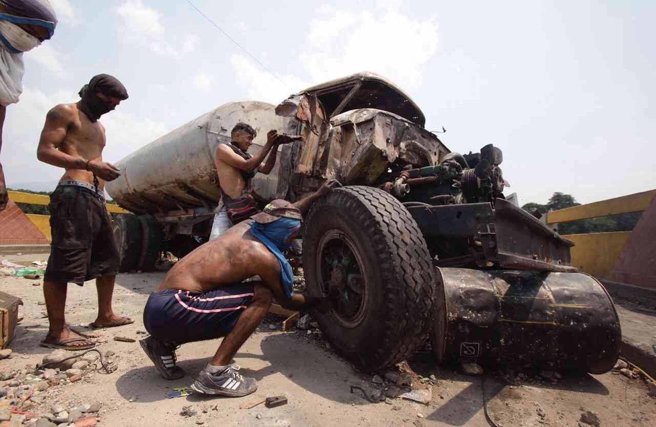 En el puente Simón Bolívar algunos manifestantes intentan rescatar cualquier cosa que sirva de los camiones quemados. Foto: Diana Rey Melo SEMANA