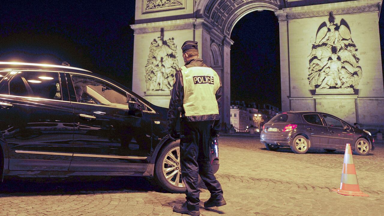 Policías franceses controlan un automóvil junto al Arco de Triunfo, cerca de los Campos Elíseos, mientras imponen un toque de queda, en París, Francia. Foto: AP / Francois Mori.