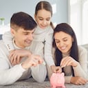 Familia feliz ahorra dinero en un cerdo alcancía. Concepto de ahorro de finanzas de dinero.