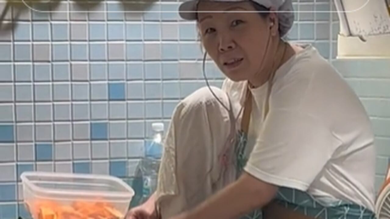 Mujer estaba con los pies sobre la mesa y al lado habían recipientes con pepinos y zanahorias picadas