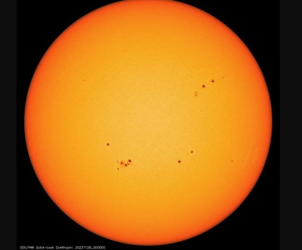 Imagen de la misión Solar Dynamics Observatory del disco solar con múltiples manchas solares, que parecen oscuras en comparación con su entorno.