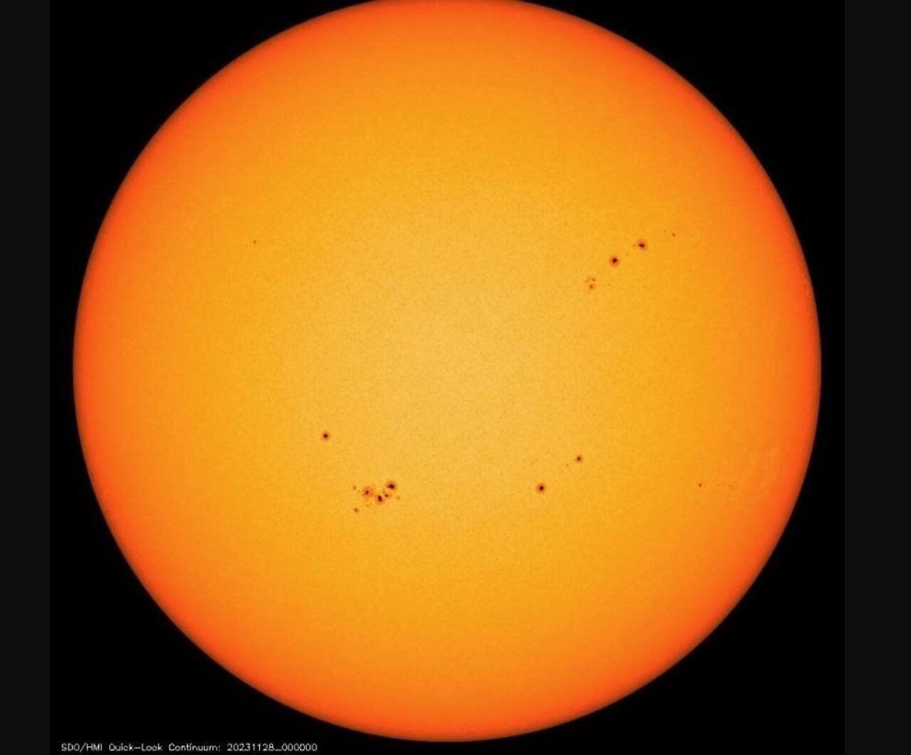 Imagen de la misión Solar Dynamics Observatory del disco solar con múltiples manchas solares, que parecen oscuras en comparación con su entorno.