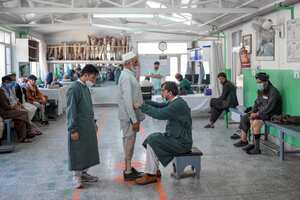 In this photograph taken on October 11, 2021, workers help a man try his new prosthetic leg at the International Committee of Red Cross Rehabilitation Centre in Kabul. - Just months ago they were fighting each other as mortal enemies, but today they are amputees dealing with their new disability, together. At this Red Cross-run rehabilitation centre in Kabul, former Afghan government soldiers and Taliban fighters adjust their new prostheses, living side by side. (Photo by BULENT KILIC / AFP) / TO GO WITH: Afghanistan-conflict-health-disability, FOCUS by Emmanuel Peuchot