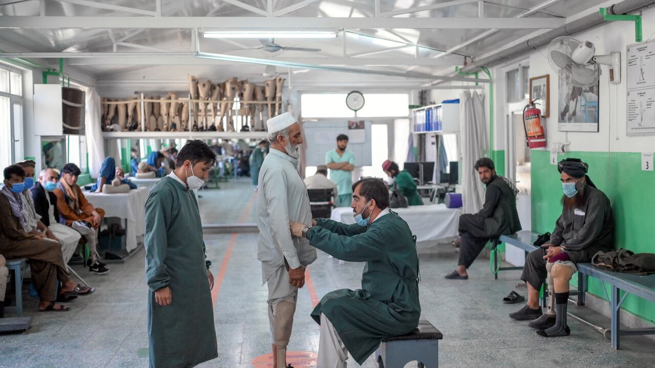 En esta fotografía, los trabajadores ayudan a un hombre a probar su nueva prótesis de pierna en el Centro de Rehabilitación del Comité Internacional de la Cruz Roja en Kabul. - Hace apenas unos meses se peleaban como enemigos mortales, pero hoy son amputados lidiando con su nueva discapacidad, juntos. En este centro de rehabilitación dirigido por la Cruz Roja en Kabul, los ex soldados del gobierno afgano y los combatientes talibanes ajustan sus nuevas prótesis, viviendo uno al lado del otro. (Foto de BULENT KILIC / AFP)