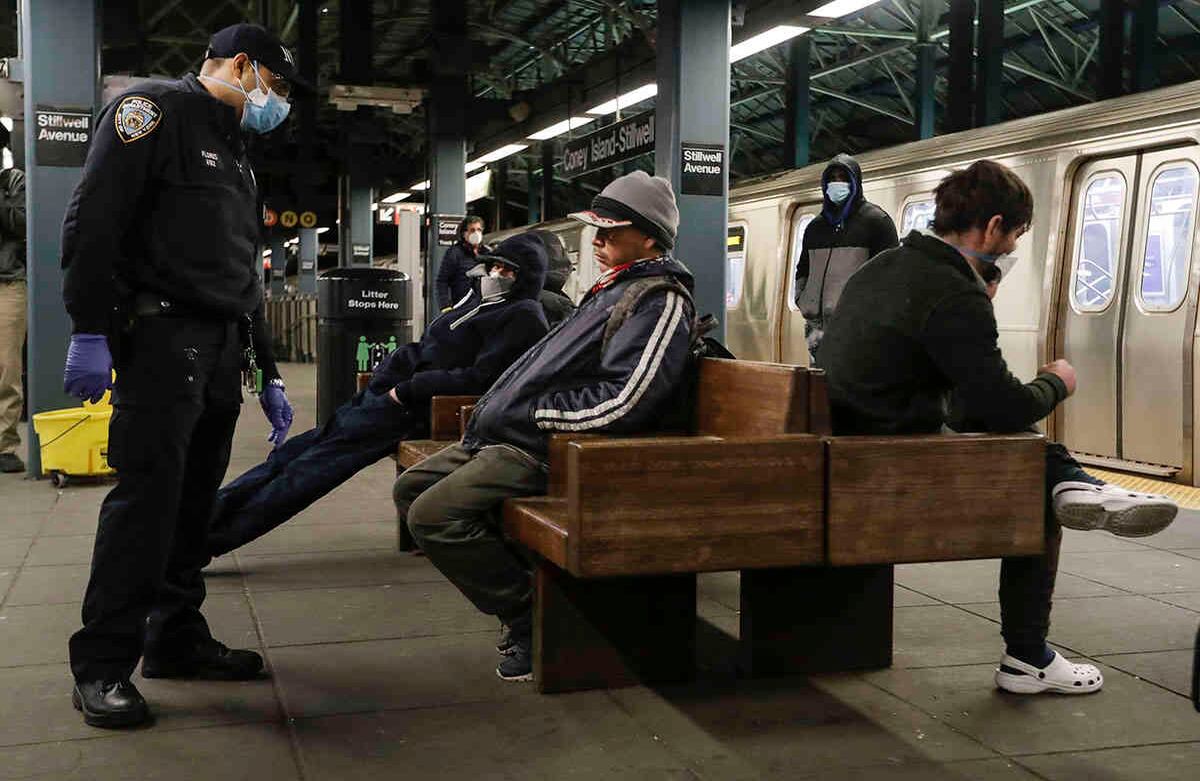 Los oficiales de policía de Nueva York hablan con la gente en la plataforma mientras los funcionarios de la MTA trabajan en trenes para las operaciones de desinfección en Coney Island, Terminal de Stillwell, el miércoles 6 de mayo de 2020, en el distrito de Brooklyn de Nueva York. Foto: Frank Franklin II/AP