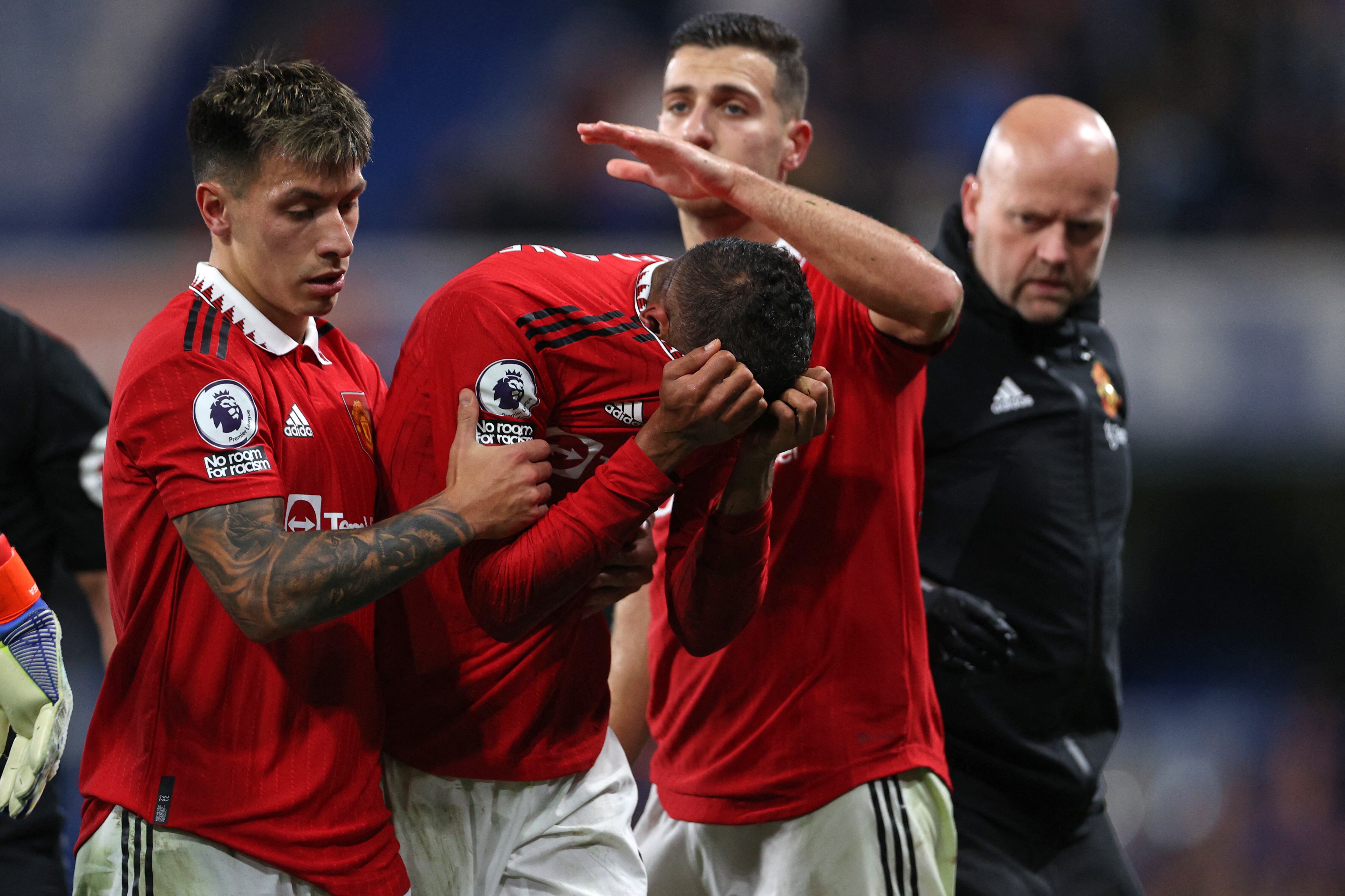 Manchester United's French defender Raphael Varane (C) is consoled by Manchester United's Argentinian defender Lisandro Martinez (L) and Manchester United's Portuguese defender Diogo Dalot (2nd R) as he leaves the pitch after picking up an injury during the English Premier League football match between Chelsea and Manchester United at Stamford Bridge in London on October 22, 2022. (Photo by ADRIAN DENNIS / AFP) / RESTRICTED TO EDITORIAL USE. No use with unauthorized audio, video, data, fixture lists, club/league logos or 'live' services. Online in-match use limited to 120 images. An additional 40 images may be used in extra time. No video emulation. Social media in-match use limited to 120 images. An additional 40 images may be used in extra time. No use in betting publications, games or single club/league/player publications. /