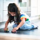 Girl (4-5) playing toy cars in kitchen