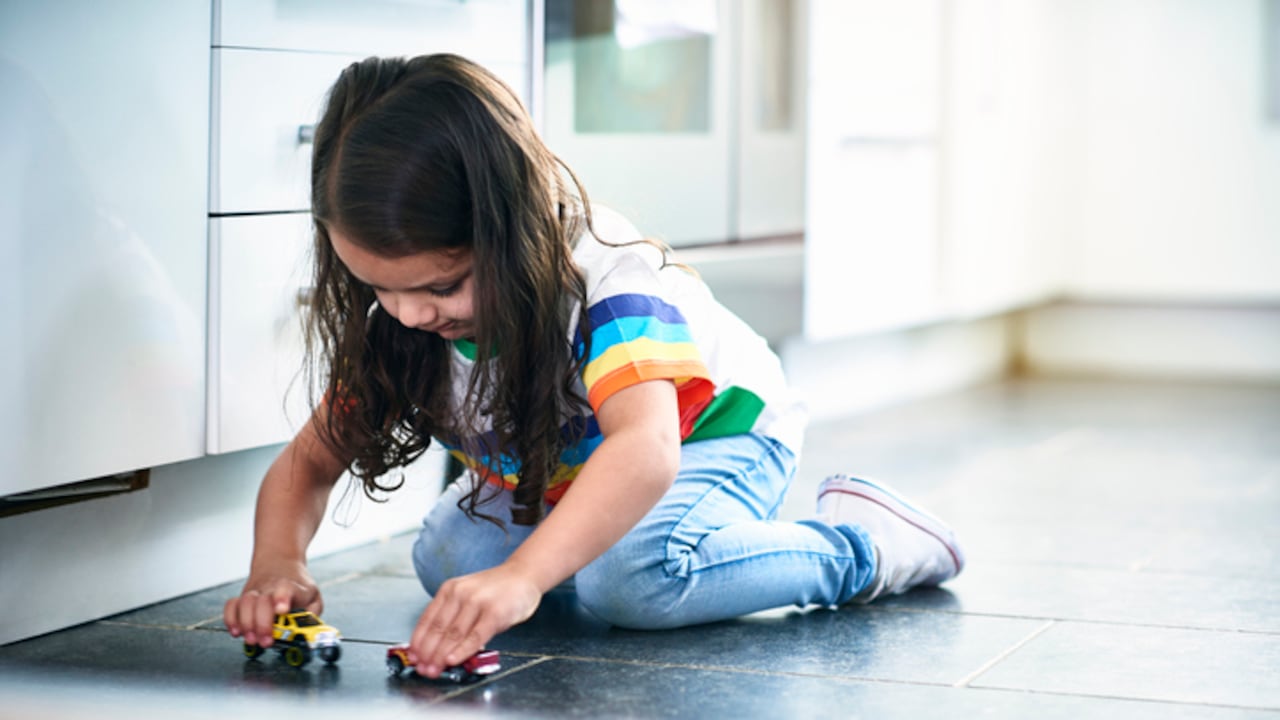 Girl (4-5) playing toy cars in kitchen