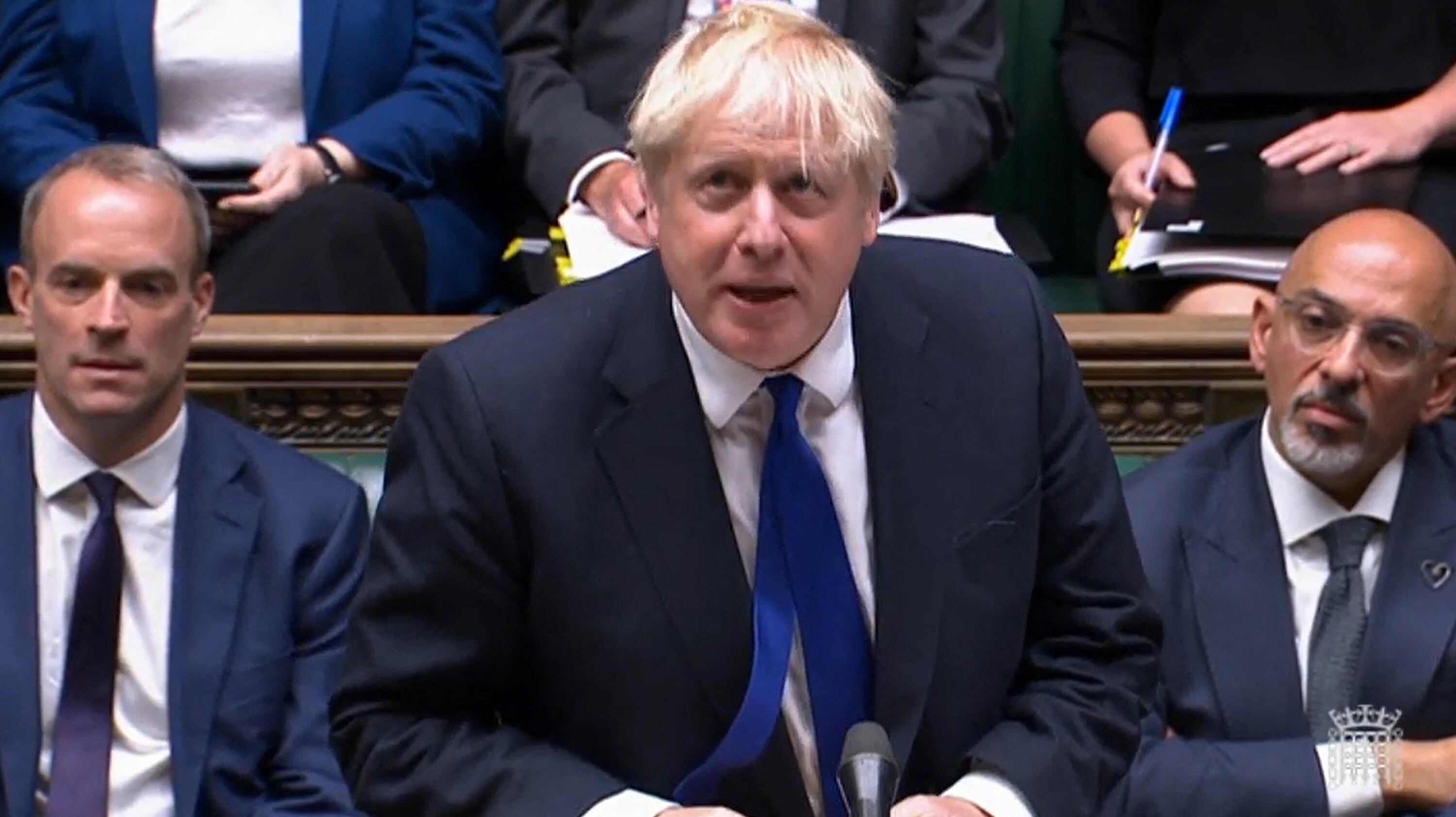 Una captura de video de imágenes transmitidas por la Unidad de Grabación Parlamentaria (PRU) del Parlamento del Reino Unido muestra al primer ministro de Gran Bretaña, Boris Johnson, hablando junto al recién nombrado Ministro de Hacienda de Gran Bretaña, Nadhim Zahawi (R) y el Secretario de Justicia y Viceprimer Ministro de Gran Bretaña, Dominic Raab (L) durante la sesión semanal de Preguntas al Primer Ministro (PMQ) en la Cámara de los Comunes de Londres el 6 de julio de 2022. - La posición de Johnson como primer ministro del Reino Unido estaba al borde del abismo, después de que dos de sus ministros principales renunciaran en protesta por el escándalo. liderazgo, acumulando presión mientras enfrentaba un interrogatorio de parlamentarios enojados. (Photo by Handout/PRU/AFP) / RESTRINGIDO A USO EDITORIAL - CRÉDITO OBLIGATORIO "AFP PHOTO/PRU" - SIN MARKETING - SIN CAMPAÑAS PUBLICITARIAS - DISTRIBUIDO COMO SERVICIO AL CLIENTE