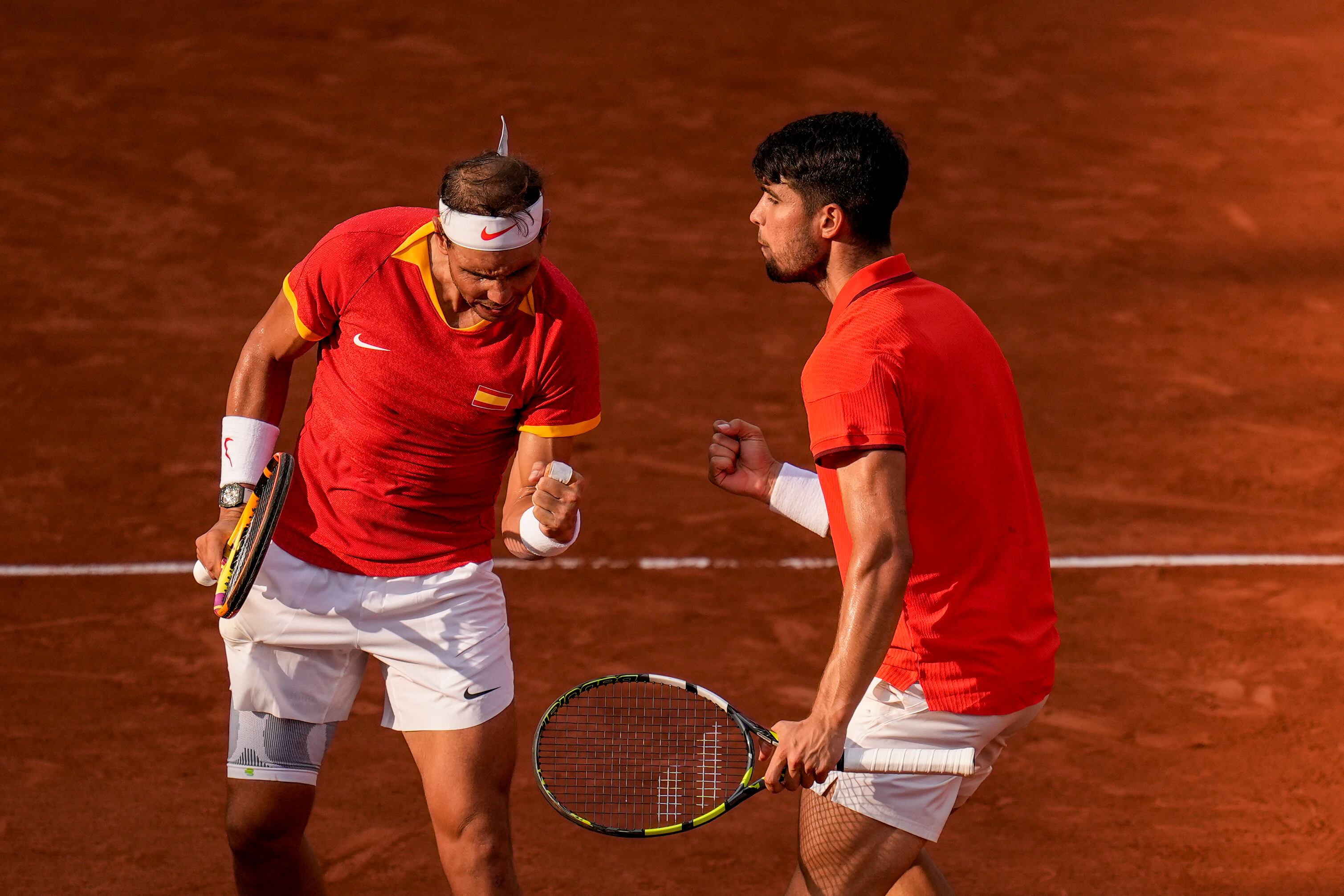 El español Carlos Alcaraz, a la derecha, y Rafael Nadal, de España celebran un punto ante Tallon Griekspoor y Wesley Koolhof de Holanda durante el partido de dobles de los Juegos Olímpicos en el estadio de Roland Garros, el martes 30 de julio de 2024, en París, Francia. (AP Foto/Manu Fernández)