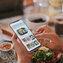 vista de ángulo alto de la mano de una mujer china asiática en la aplicación móvil para la entrega de alimentos en línea durante la hora del desayuno