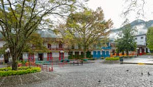 Plaza principal de Jardín, Antioquia, Colombia. Vegetación, coloridas fachadas y casas coloniales, árboles, nubes.