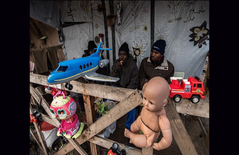 Inmigrantes sudaneses comen en su estrafalaria choza. Foto: Philippe Huguen / AFP