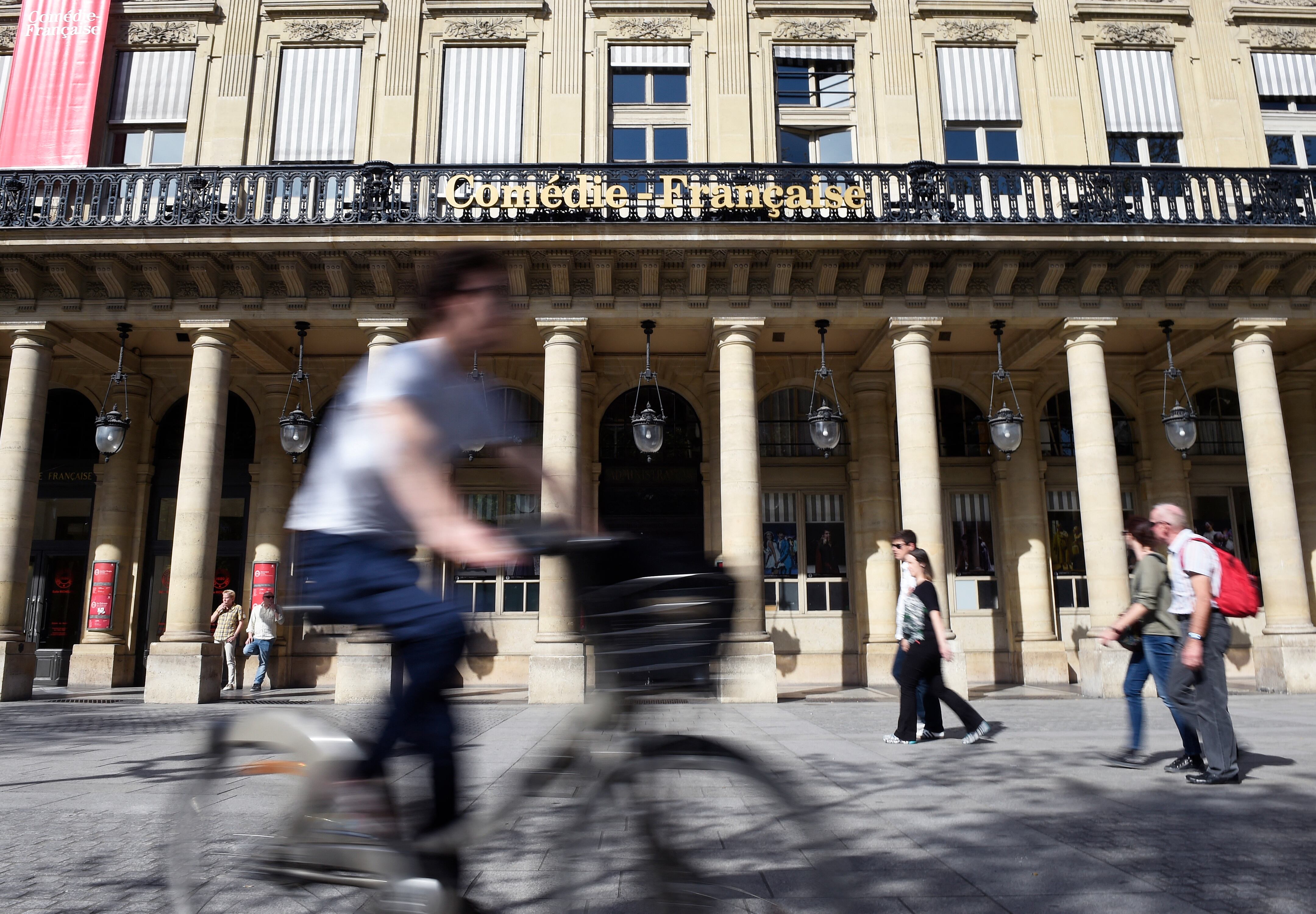 (FILES) This file photo taken in Paris on April 15, 2015 shows a man cycles past the Theater institution La Comedie-Francaise. - La Comedie-Francaise is the oldest theatre company in the world. Called the 'house of Moliere' even though he never went there, the theatre has been haunted by Moliere for almost 400 years. (Photo by Loic VENANCE / AFP)