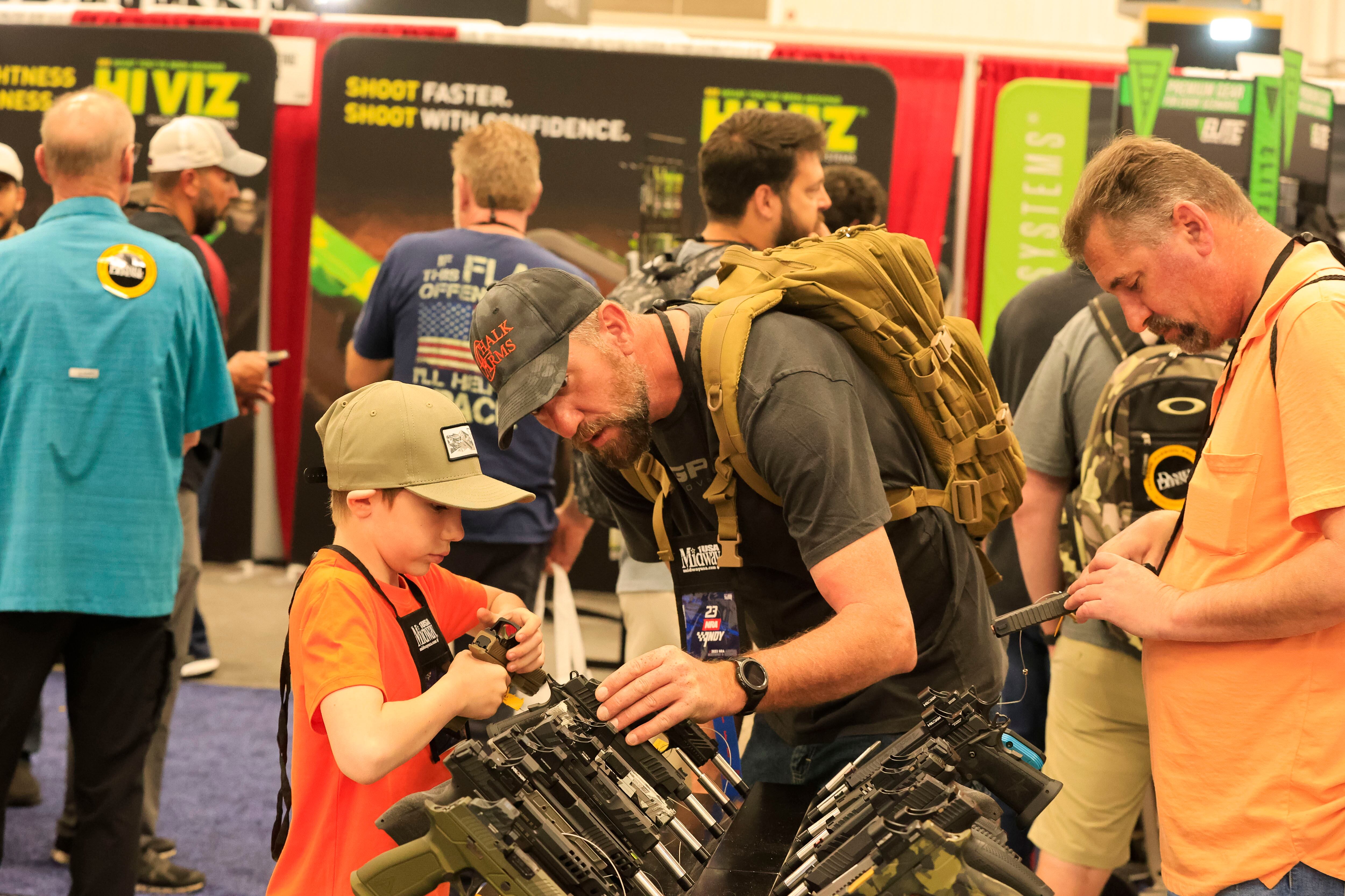 Un hombre ayuda a un niño a mirar una pistola durante las Reuniones y exposiciones anuales de la Asociación Nacional del Rifle en el Centro de Convenciones de Indiana en Indianápolis