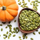 Pumpkin seeds in a wooden bowl on a white table