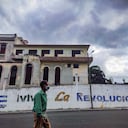 A man wearing a face mask walk past a graffiti reading "Long Live The Revolution!" in Havana, on April 6, 2021. - Amidst long queues for food and the effects of the pandemic, Cubans view without much hope the change of baton between Raul Castro and Miguel Diaz-Canel as first secretary of the Cuban Communist Party, the highest office in the country. (Photo by YAMIL LAGE / AFP)