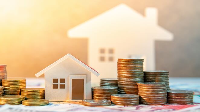 Inversión inmobiliaria o inmobiliaria. Tasa de préstamo hipotecario para vivienda. Ahorrar dinero para el concepto de jubilación. Pila de monedas en billetes internacionales con modelo de casa en la mesa. Fondo de crecimiento empresarial