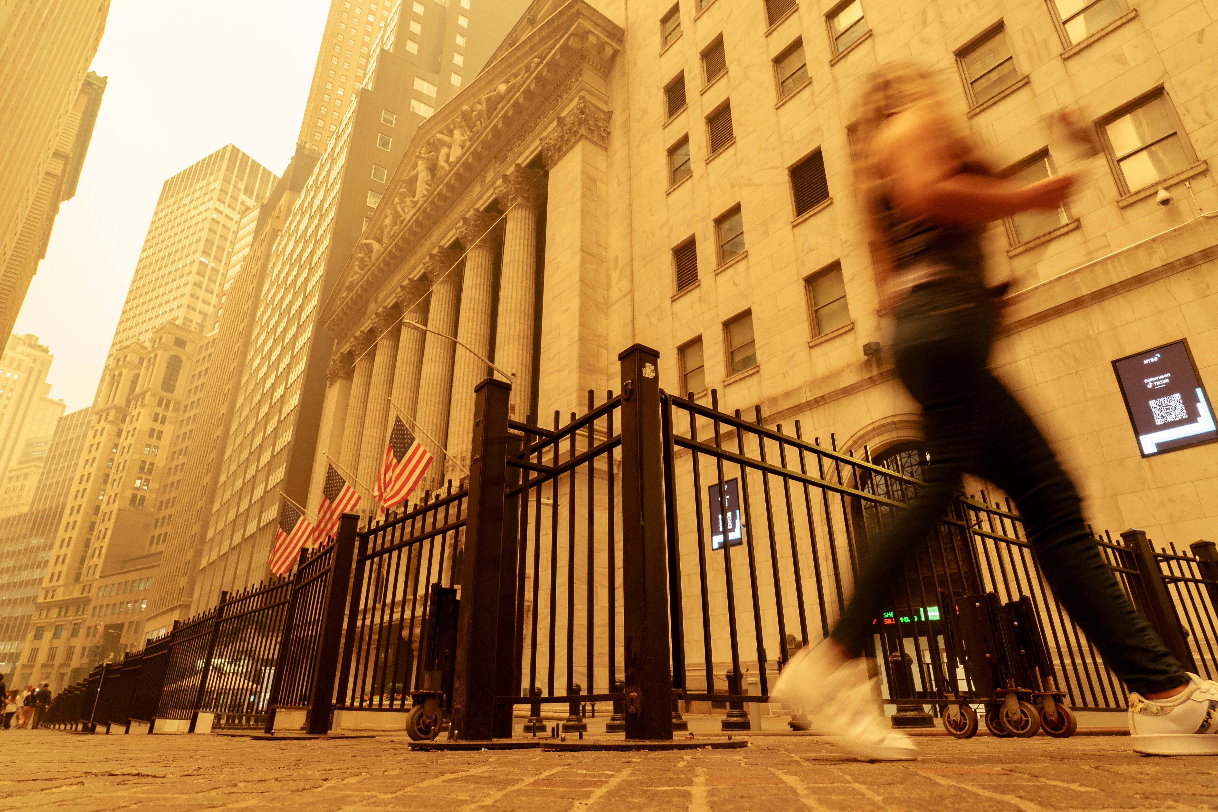 Una transeúnte camina entre el humo y la bruma cerca de la Bolsa de Valores de Nueva York, el miércoles 7 de junio de 2023. (AP Foto/J. David Ake)