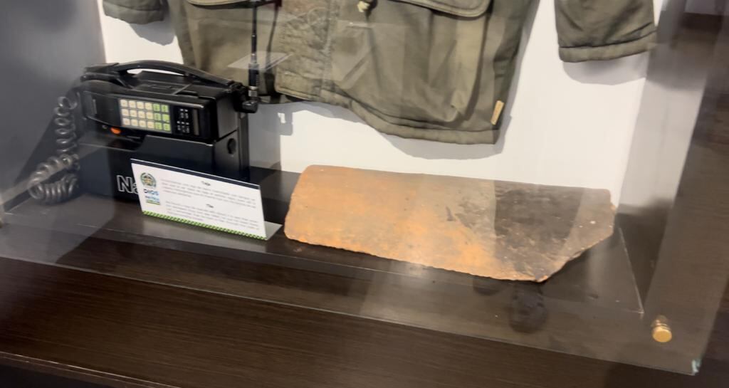 A la izquierda el teléfono con el que Pablo Escobar llamó a su hijo por últimas vez y que reveló su ubicación. Al lado un pedazo de teja con la sangre de escobar del día de su muerte.