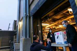 Un conductor de FedEx levanta el pulgar después de entregar una caja que contiene la vacuna Pfizer-BioNTech COVID-19 a los farmacéuticos Richard Emery, derecha, y Karen Nolan cuando llega al Hospital de Rhode Island en Providence, RI, el lunes 14 de diciembre de 2020. Foto: AP / David Goldman.