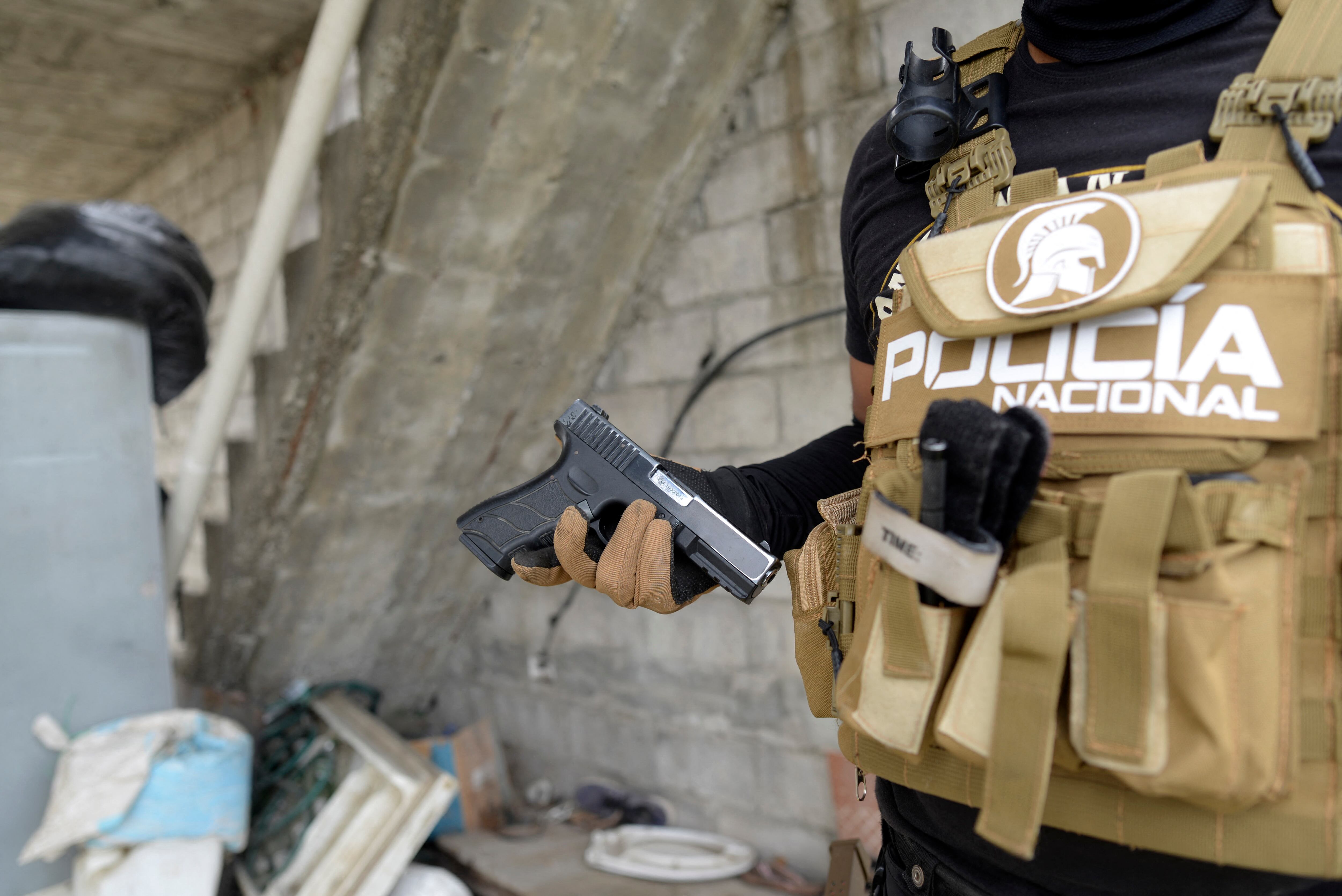 (FILES) A police officer shows a gun during a security operation against drug trafficking in Duran, Ecuador, on July 17, 2024. The mood is tense in the violent coastal town of Dur�n, which is guarded by soldiers and police. The small city, located on the banks of the Guayas River, is prized by drug traffickers for its estuaries, which have been converted into river routes to ports from which drugs are shipped. (Photo by Gerardo MENOSCAL / AFP)