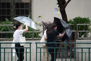 In this photo released by Xinhua News Agency, residents walk against strong wind and rain as Typhoon Talim approaches in Macao in southern China on Monday, July 17, 2023. Schools and the stock market were closed in Hong Kong on Monday as Typhoon Talim sideswiped the city and headed toward landfall on the Chinese mainland and the island province of Hainan. (Cheong Kam Ka/Xinhua via AP)