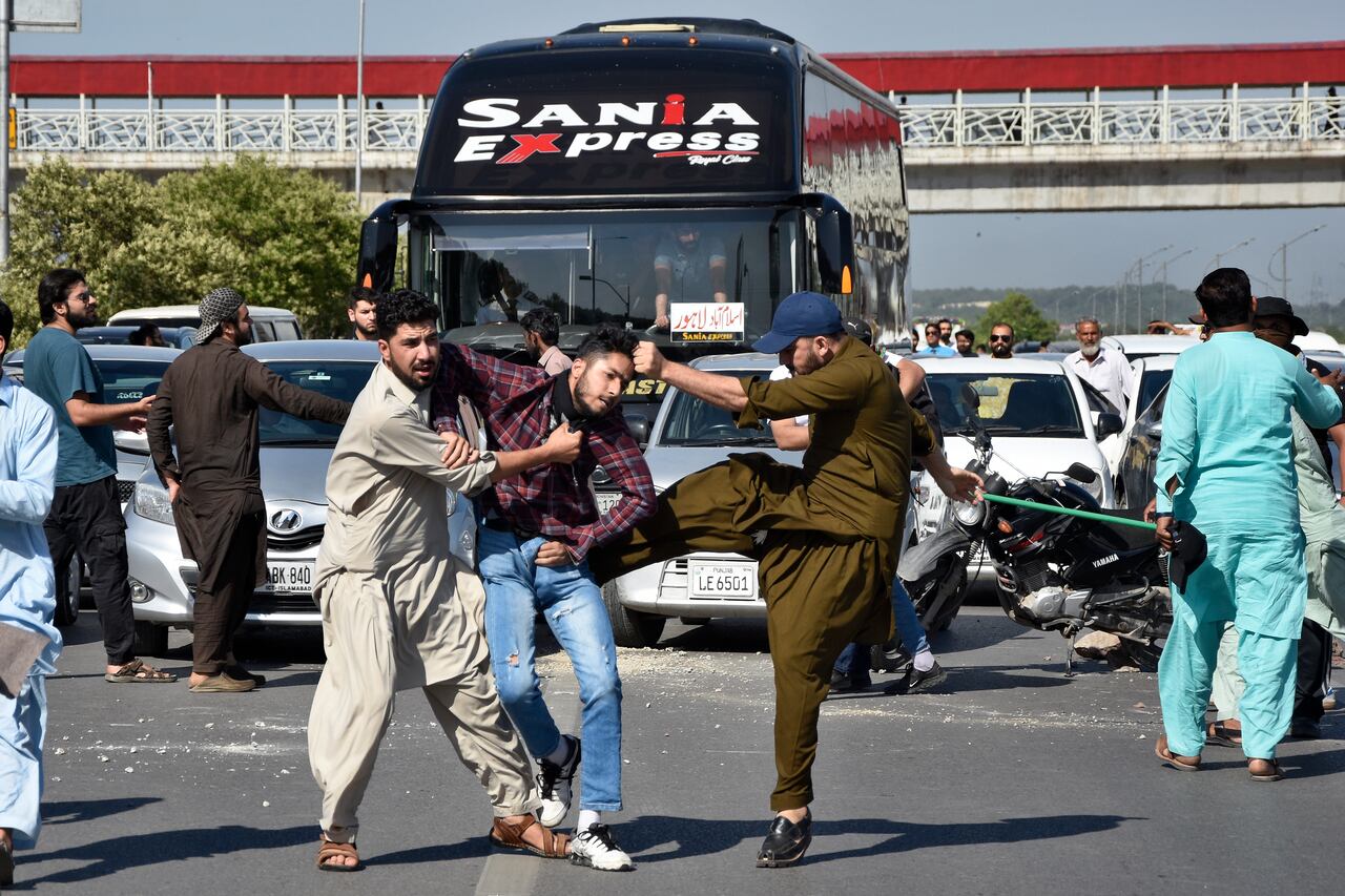 Policías vestidos de civil golpean a un partidario del ex primer ministro de Pakistán, Imran Khan, mientras lo detienen cuando él y otros bloquean una carretera como protesta