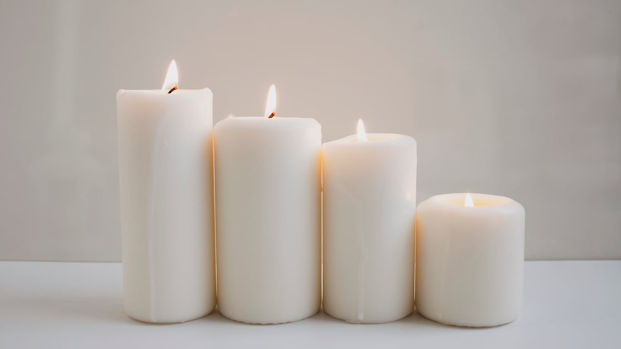 Grandes velas ardientes en el fondo de una pared blanca. Imagen de referencia.