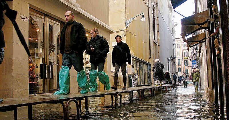 Algunos tuirstas caminan por un distrito comercial inundado en 2005. Foto por Spencer Platt/ Getty Images.