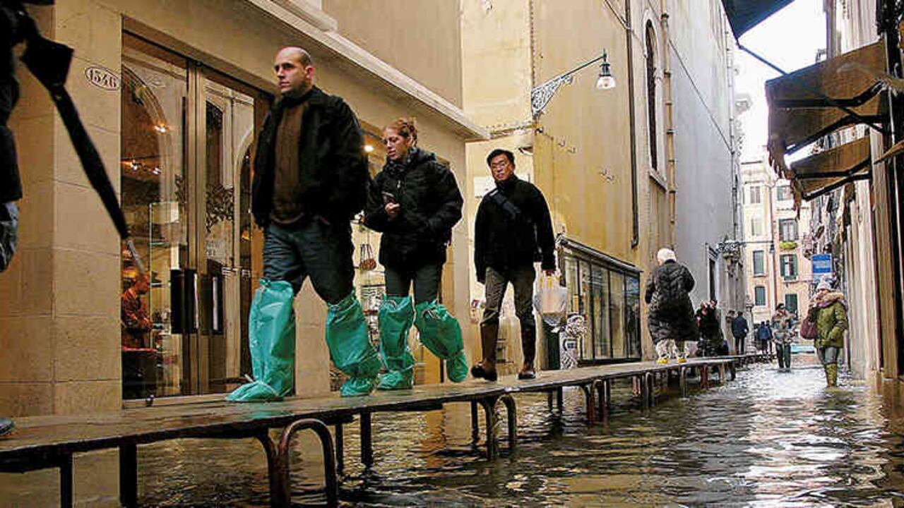 Algunos tuirstas caminan por un distrito comercial inundado en 2005. Foto por Spencer Platt/ Getty Images.