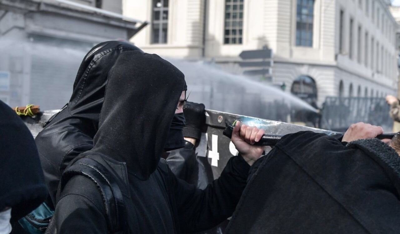 Los manifestantes se defienden con escudos de los chorros de agua que lanzan las autoridades